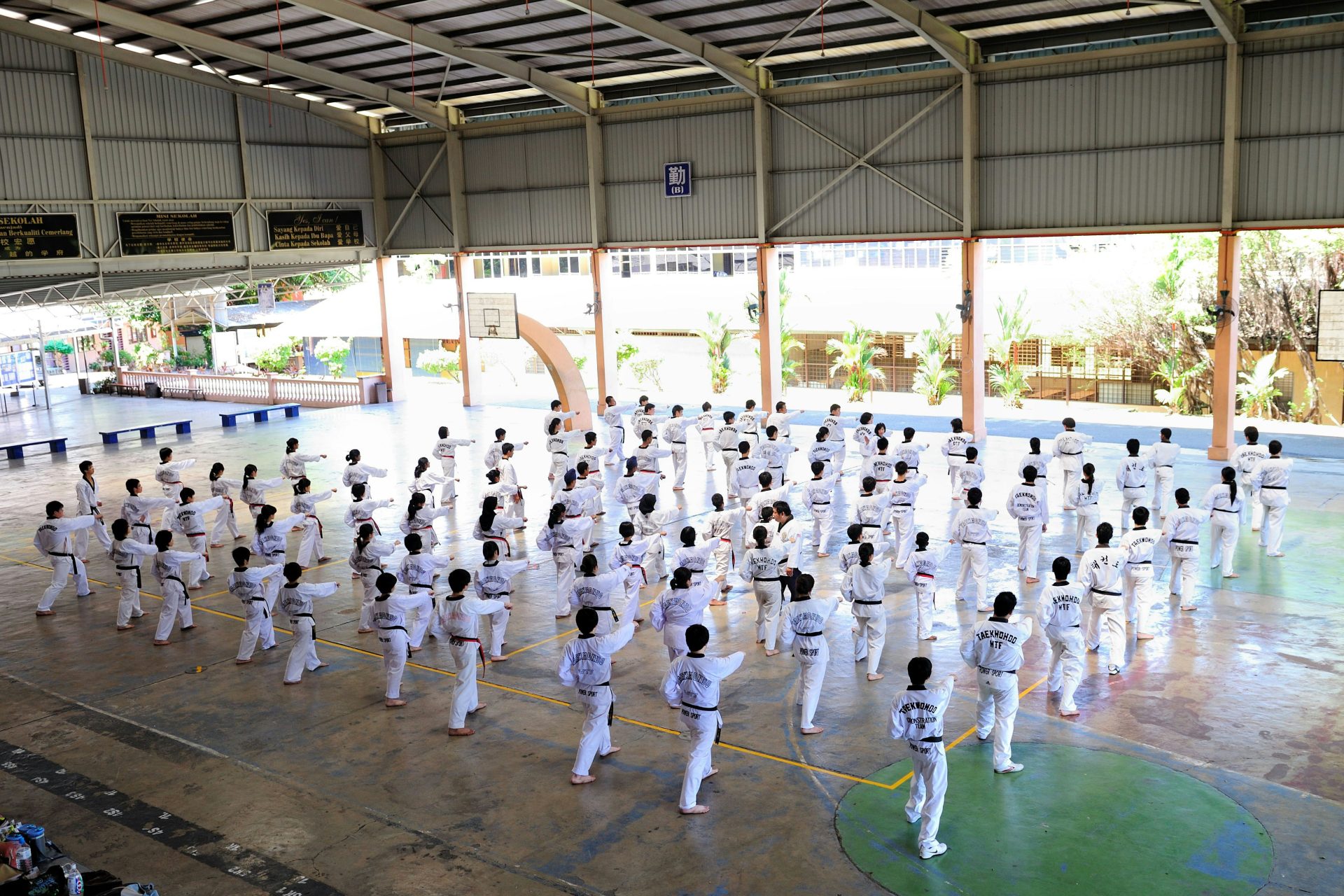 a group of people in white karate uniforms in a room with trees